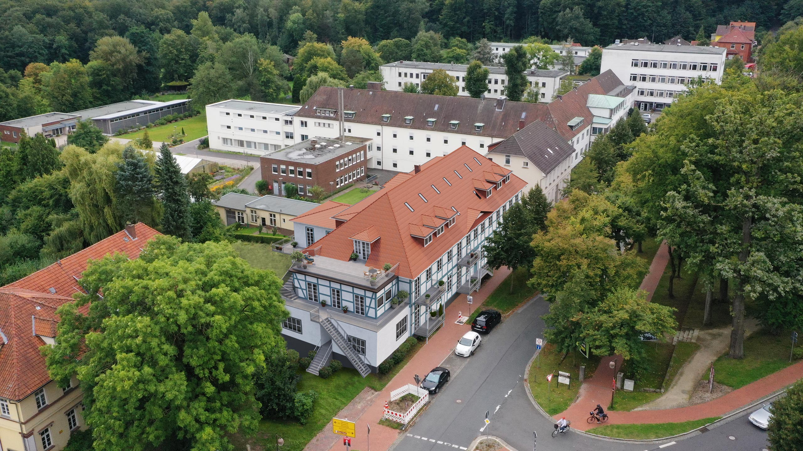 Luftbild einer Wohnanlage zwischen Bäumen, mehrere Gebäude um einen Innenhof.