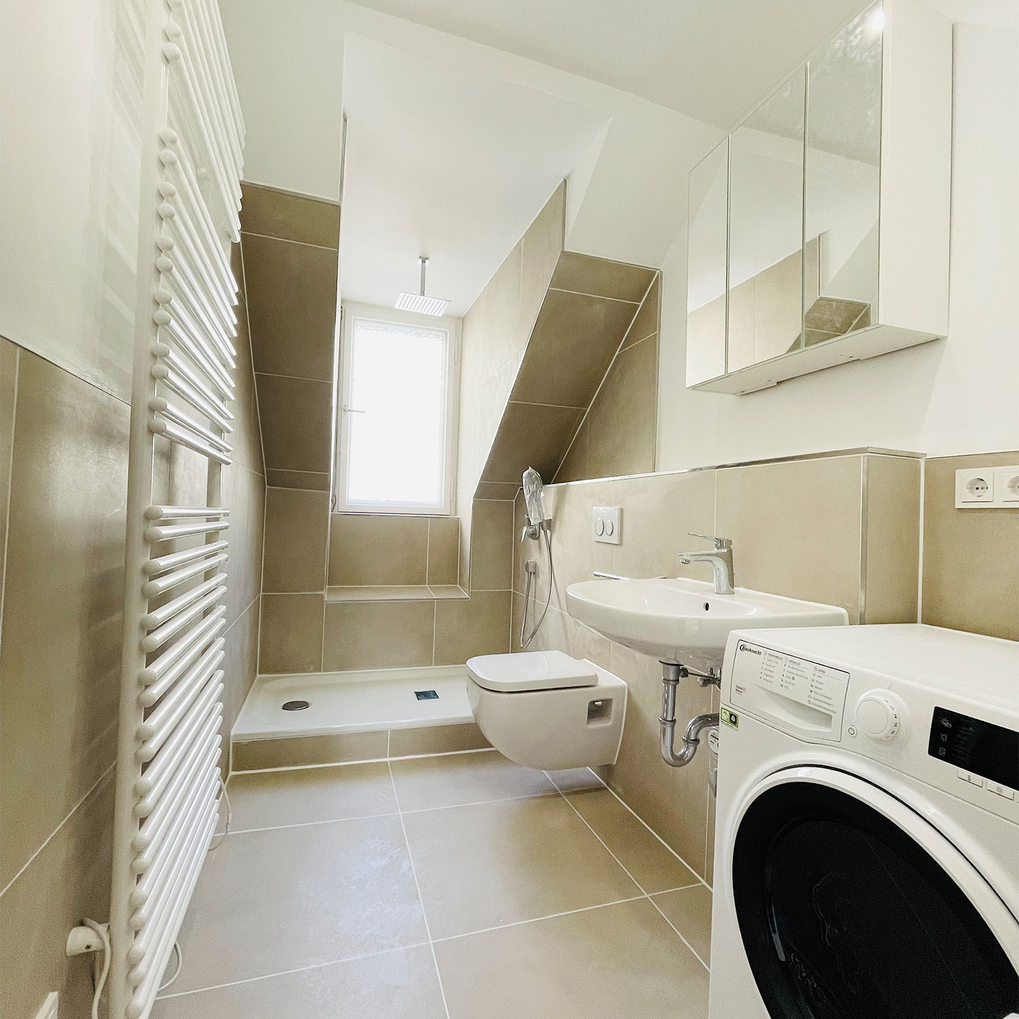 Badezimmer unter einer Dachschräge, mit bodengleicher Dusche, Waschbecken und Waschmaschine