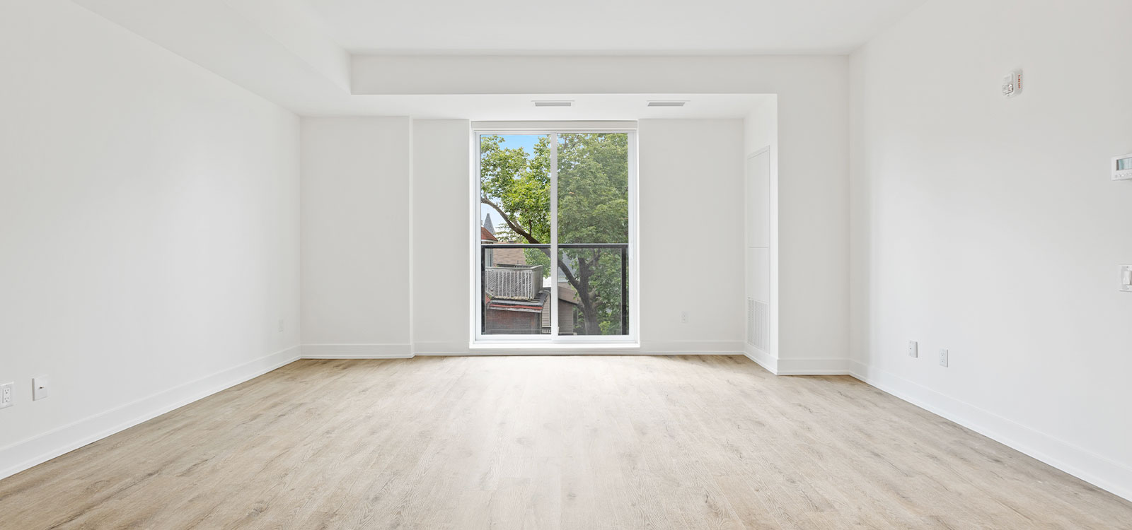 Ein leerer, frisch renovierter Raum mit Fenstertür und hellem Boden.